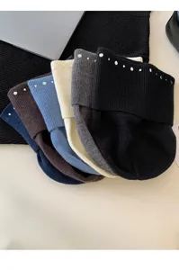 Gros plan sur des bonnets en tricot tendance avec rivets métalliques, matière douce et chaude.