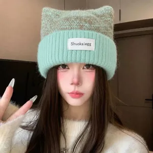 Gros plan détaillé du bonnet en tricot oreilles de chat vert clair et marron avec patch.
