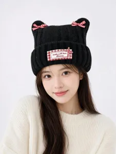 Cute black knitted cat ear hat with red plaid bows and label detail for sweet everyday winter style.