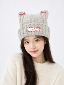 Detailed closeup of stylish grey knit cat ear beanie with red plaid bows and custom label.