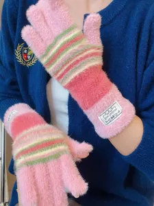 Gros plan de gants d'hiver douillets en tricot pelucheux à rayures roses et chaudes.