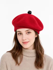 Red wool beret detail shot, cute black white top ball accent, stylish winter fashion hat.