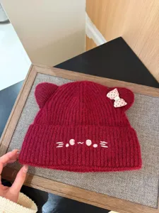 Cómodo gorro de punto rojo con orejas de gato, cara bordada y lindo lazo de lunares.
