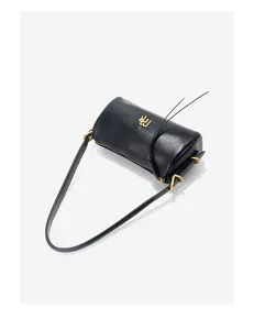 Close-up detail of the black cylindrical leather shoulder bag showing gold metal hardware.