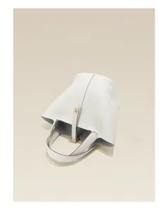 Close-up of white genuine leather bucket bag, showcasing pebbled texture and metal clasp.