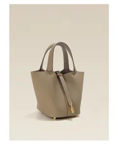 Detail view of the genuine leather bucket handbag featuring top handles and a secure lock closure.
