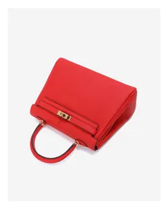 Detail van rode leren Kelly tas met goudkleurige hardware en getextureerd nerfleder.