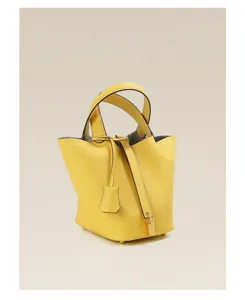 Detail shot of yellow genuine leather bucket bag, classic design with padlock and double handles.