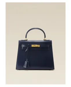 Gros plan d'un sac à main en cuir bleu marine brillant avec des détails dorés chic.