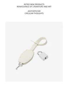 Minimalist leather clochette key ring and silver padlock detail accessory for bag decoration.