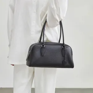 Elegant black leather bowling shoulder bag for women, minimalist long handle design.