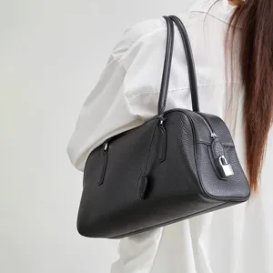 Women black leather bowling bag boston shoulder bag with long handle and metal lock detail.