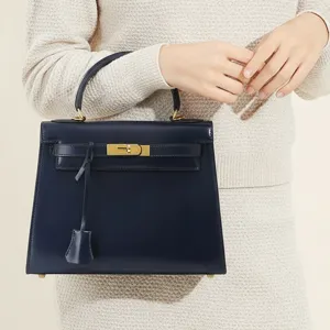 Sac à main classique en cuir bleu marine avec forme trapèze structurée et détails dorés.