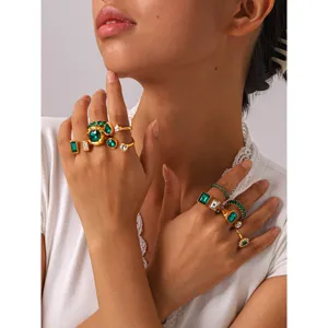 Gros plan sur un ensemble de bagues vintage dorées serties de zircons verts et blancs brillants.