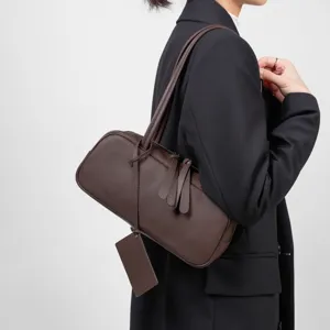 Detailed view of the elegant brown leather underarm bag, showing smooth texture and double straps.