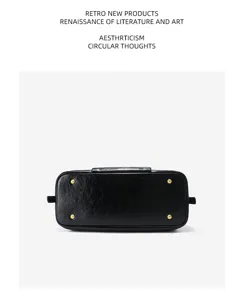 Detail shot of the bottom of a black leather Boston handbag with metal feet for durability.