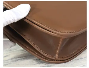 Close-up detail of brown leather cross-body bag, showcasing fine stitching and gusset.