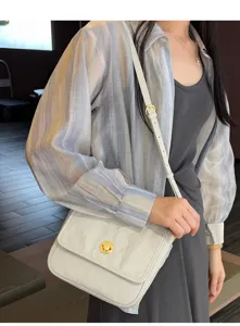 Detail view of the elegant white crinkled shoulder bag with luxury gold turn-lock clasp.