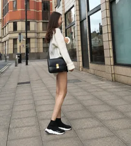 Outdoor street detail view showcasing a black leather crossbody square bag worn by model.
