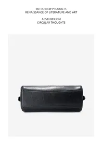 Detail view of black leather cylinder pillow bag, premium cowhide texture, elegant hardware.