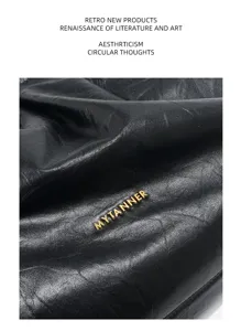 Genuine leather black pleated tote bag detail shot, premium cowhide hobo shoulder handbag.