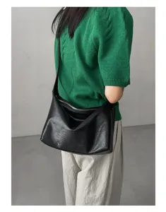 Detailed view of a stylish black leather hobo shoulder bag worn by a model in casual wear.