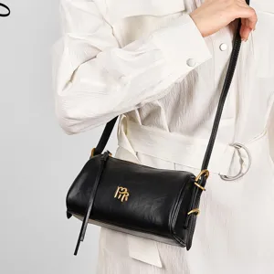 Black cylindrical leather shoulder bag, chic underarm baguette bag for women commuting.