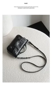 Black leather motorcycle crossbody bag with metal buckles and studs, chic urban style.