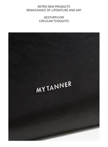 Detailed view of black genuine leather handbag surface, showing fine texture and metal logo.