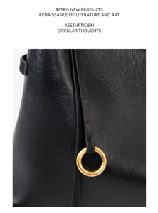 Close-up detail of black leather tote bag featuring elegant gold ring accent and fine grain texture.