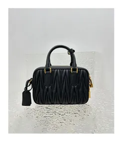Black quilted leather mini bowling bag detail view with gold hardware and top handle design