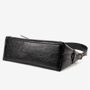 Closeup detail of black crumpled leather shoulder bag showing texture and hardware strap.