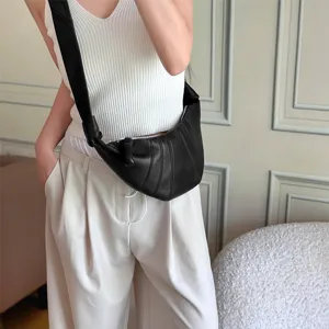 Schwarze Leder Croissant Umhängetasche quer über den Körper getragen von Model im lässigen Outfit.