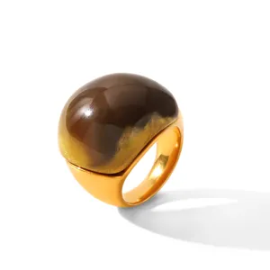 Bague tendance avec dôme en résine marron poli et anneau épais en acier inoxydable doré.