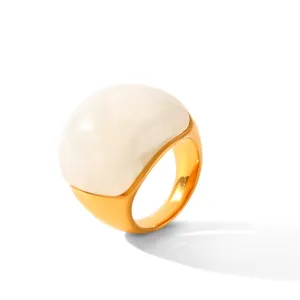 Gros plan d'une bague dôme dorée massive avec un superbe détail supérieur blanc et lisse.