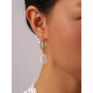 Close-up detail of stainless steel baroque pearl hoop earrings with gleaming crystal accent.
