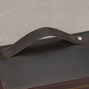 Close-up detail of genuine leather handle, fine stitching and metal rivet on wallet or bag.