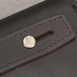 Close-up detail of vintage genuine leather wallet showcasing metal button and fine stitching.