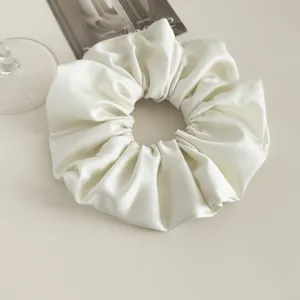 White satin hair scrunchie detail shot, elegant shiny hair accessory for women.