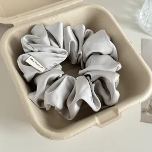Graues Satin-Haargummi mit Stoffetikett, weich gefaltetes Haargummi für elegante Alltagsfrisuren.