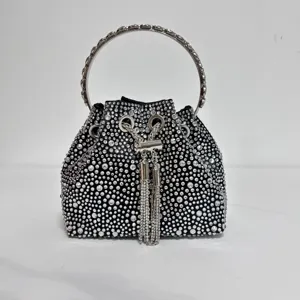 Detailed shot of black rhinestone evening bucket bag with metal ring handle and sparkling tassels.