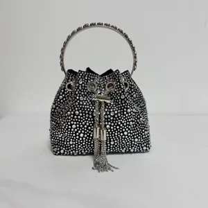 Close-up detail of rhinestone bucket bag with metal ring handle and sparkling crystal fringes.