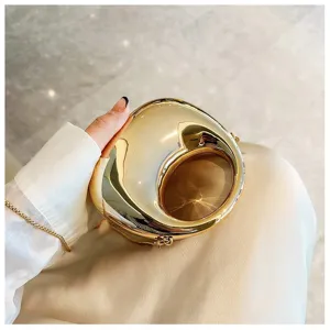 Metallic gold mini handbag detail shot, stylish pebble shaped crossbody chain bag accessory.