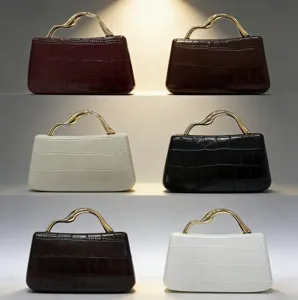 Detalles del lujoso bolso con estampado de cocodrilo, asa dorada y textura elegante.