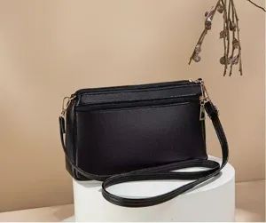 Detailed view of the black multi-layer zippered women shoulder bag, elegant pebbled leather.