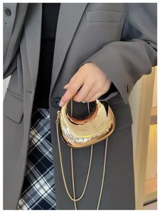 Detail view of a stylish metallic gold mini handbag with a delicate chain strap and chic shape.