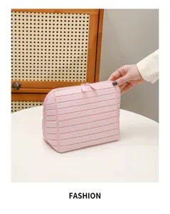 Vista di dettaglio della borsa cosmetica rosa con texture geometrica e doppia chiusura lampo.