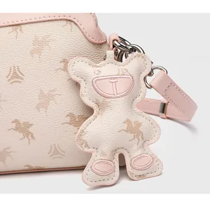 Detailopname van schattige berensleutelhanger en pegasusprint op de stijlvolle leren tas.