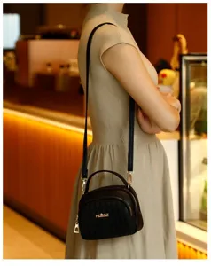 Detail view of black quilted crossbody shoulder bag with multi-layer zipper and gold hardware.