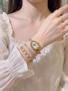 Detailansicht der goldenen ovalen Quarzuhr für Damen mit eleganten Armbändern und Ring.